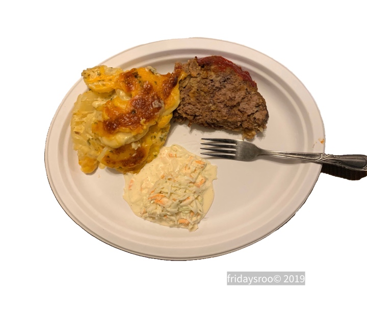 Meatloaf, scalloped potatoes, and coleslaw on a paper plate with a fork